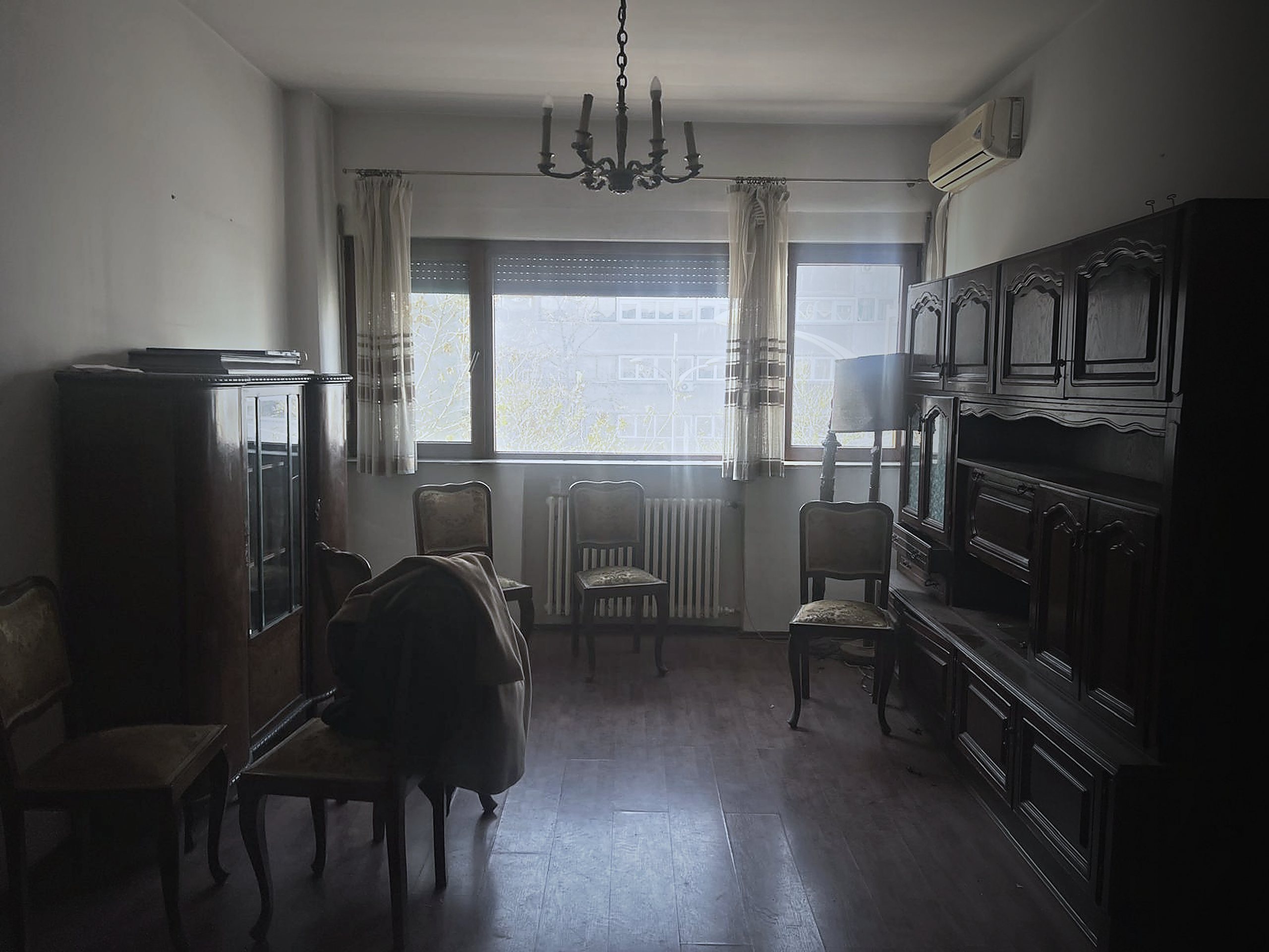 Livingul apartamentului înainte de renovare: mobilier vechi, parchet uzat, tavan cu candelabru.