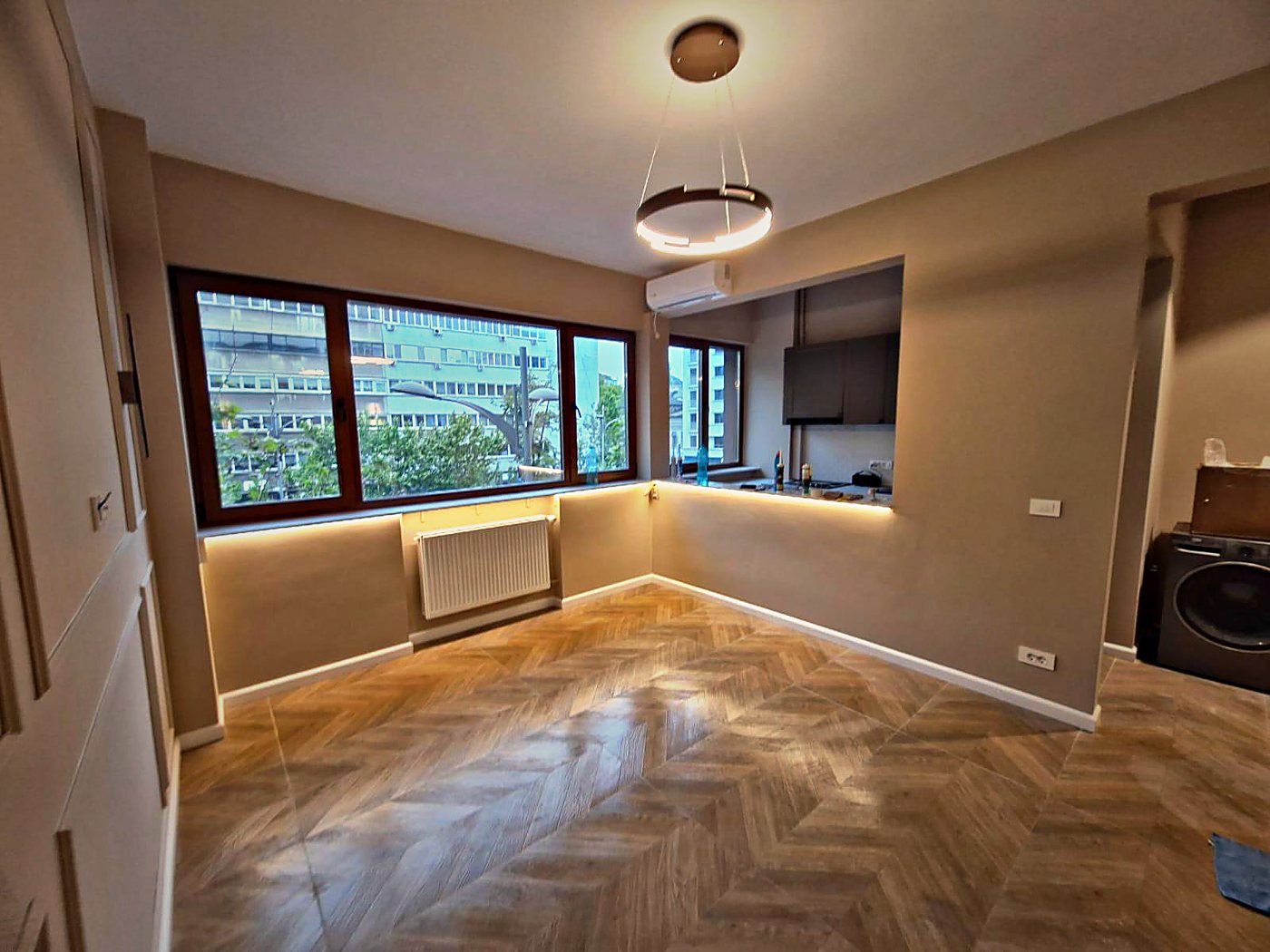 Zona de zi deschisă către bucătărie, cu parchet în spic